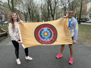 From left, Katelynn Ledford-McCoy and Kallup McCoy hold up the Eastern Band of Cherokee Indians flag while visiting Boston for the 127th Boston Marathon.
