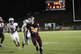 Maroon Devil Josh Collins runs with the ball at the home football game on homecoming night, pursued by several opposing Wildcats.