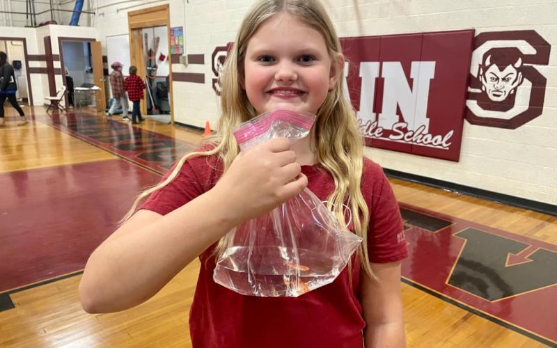Hollyn Rutkosky grins ear to ear as she holds a fish she won from throwing a ping pong ball into a fish bowl at the Fall Festival