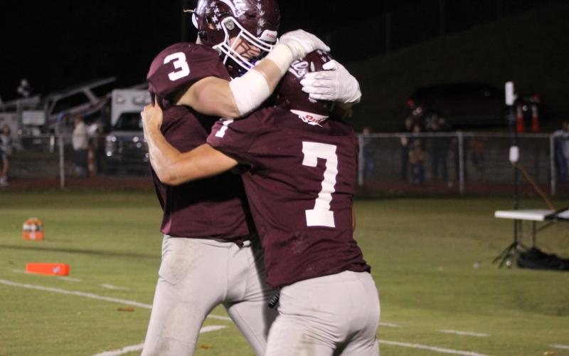 Josh Collins (from left) and James Stroman celebrate a touchdown at the game against the Cherokee Braves on Friday, Oct. 20, which the Maroon Devils won 45-7.