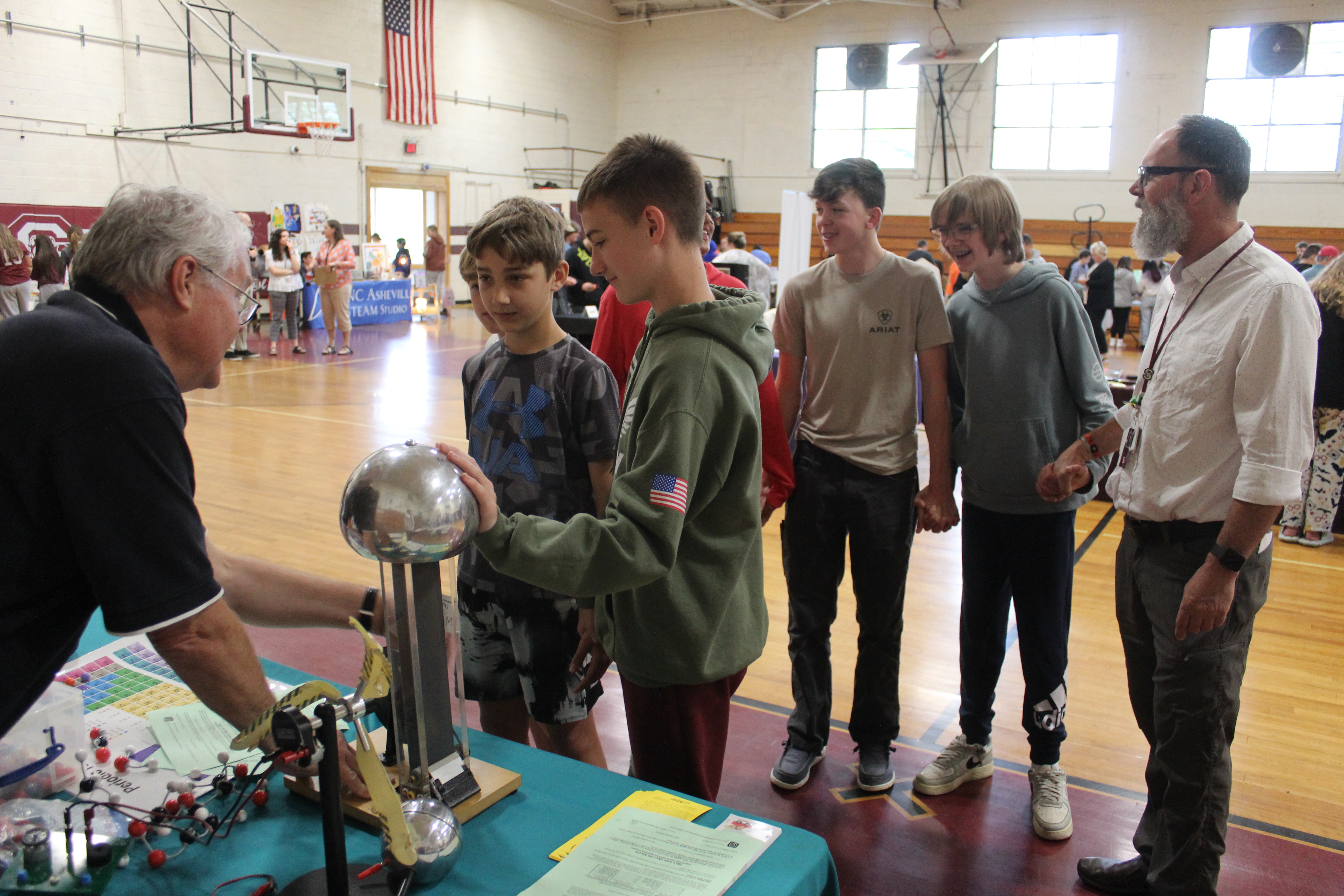 A group of students and a teacher try out the static electricity device at a booth from the NC Division of Air Quality. 